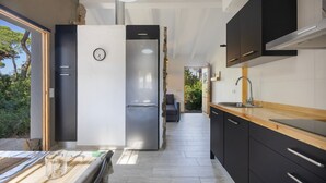 Une cuisine moderne équipée d’un réfrigérateur, d’un évier et d’un plan de travail en bois.