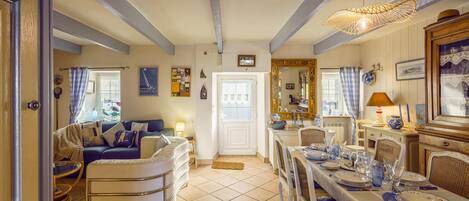 A cozy living room with a sofa, a dining table set for four, and a kitchen area with a stove and cabinets.