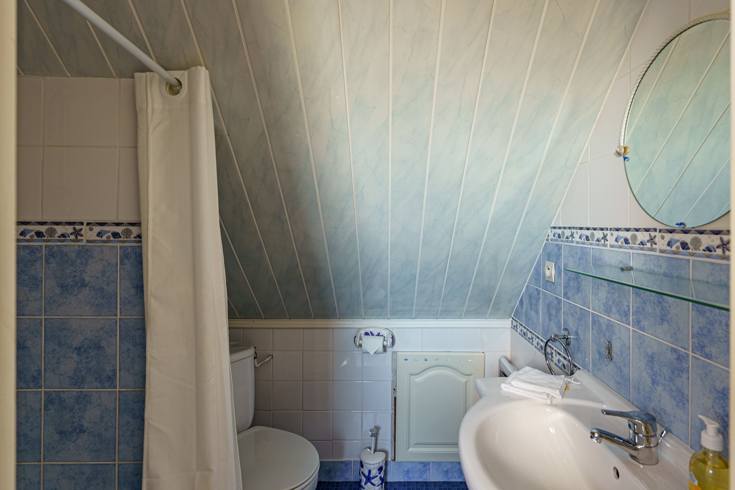 Een badkamer met toilet, wastafel en douchegordijn.
