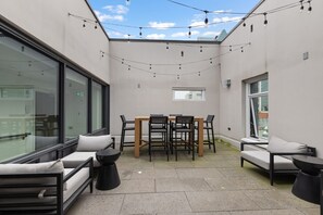 Eine moderne Außenpatio mit Esstisch und Stühlen, einer Couch und einem kleinen Fenster.