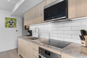 Eine moderne Küche mit Mikrowelle aus Edelstahl, einem Backofen, einer Spüle mit Wasserhahn und einem Messerblock.