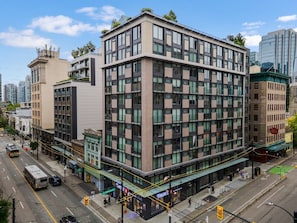 A multi-story building with a modern architectural style, featuring a mix of glass and brick facade, located in an urban setting with a street in front. - The Downtown Haven – 2BR at Richard & Pender (Vancouver)