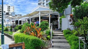 A waterfront restaurant with outdoor seating, a sign for 'Chill Cafe 89 Weekend Specials', and a 'Welcome' sign above the entrance. - It's Five O'Clock Somewhere (Sunshine Coast)