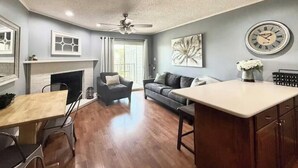 A spacious living room with a fireplace, a dining area, and a kitchen counter. - River Front Condo Walking Distance to Downtown (New Braunfels)