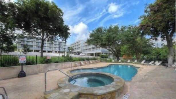 A swimming pool with a hot tub, surrounded by lounge chairs and trees. - River Front Condo Walking Distance to Downtown (New Braunfels)