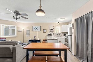 A compact living space with a dining table, sofa, kitchenette, and ceiling fan. - Eight on the Bay 2B (Ocean City)