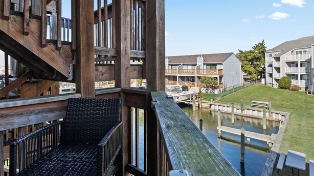 Un pontile in legno con vista su una marina, barche, una zona verde e edifici moderni sullo sfondo.