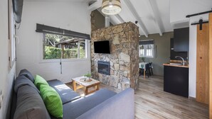 A modern living space with a stone fireplace, a flat-screen TV, a sofa, and a dining area. - Casa Espartosa 1 in Chiclana with Private Pool, Terrace, and Wi-Fi (Chiclana de la Frontera)