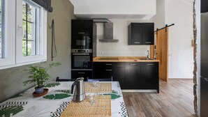 A modern kitchen with black cabinets, a wooden countertop, and a built-in oven. - Casa Espartosa 1 in Chiclana with Private Pool, Terrace, and Wi-Fi (Chiclana de la Frontera)