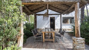 A wooden deck with a table and chairs, surrounded by greenery. - Casa Espartosa 1 in Chiclana with Private Pool, Terrace, and Wi-Fi (Chiclana de la Frontera)