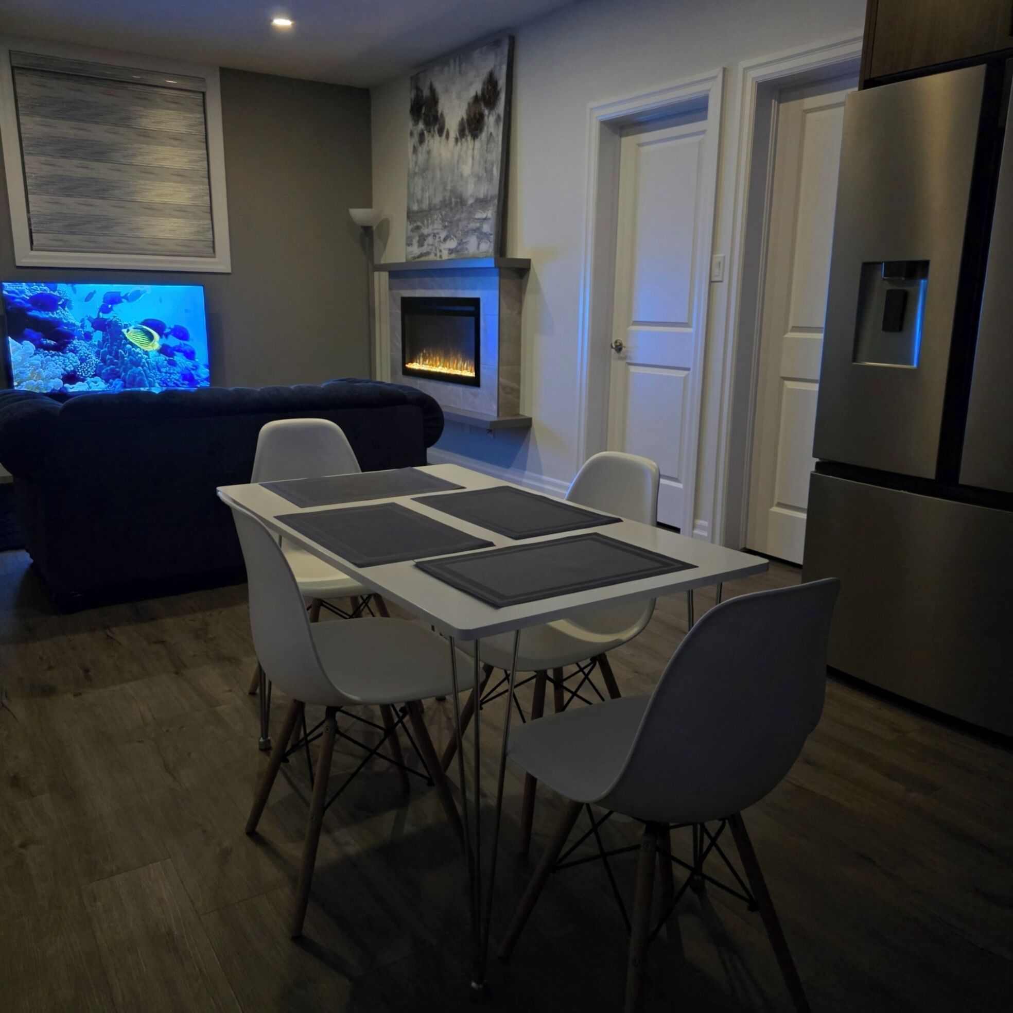 A modern kitchen with a dining area, a fireplace, and a television.
