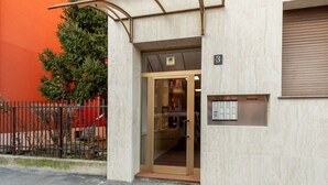 Entrada de un edificio con puerta de cristal, buzón y placa con un número.
