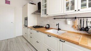Una cocina con armarios blancos, encimera de madera, un lavabo y una estufa.
