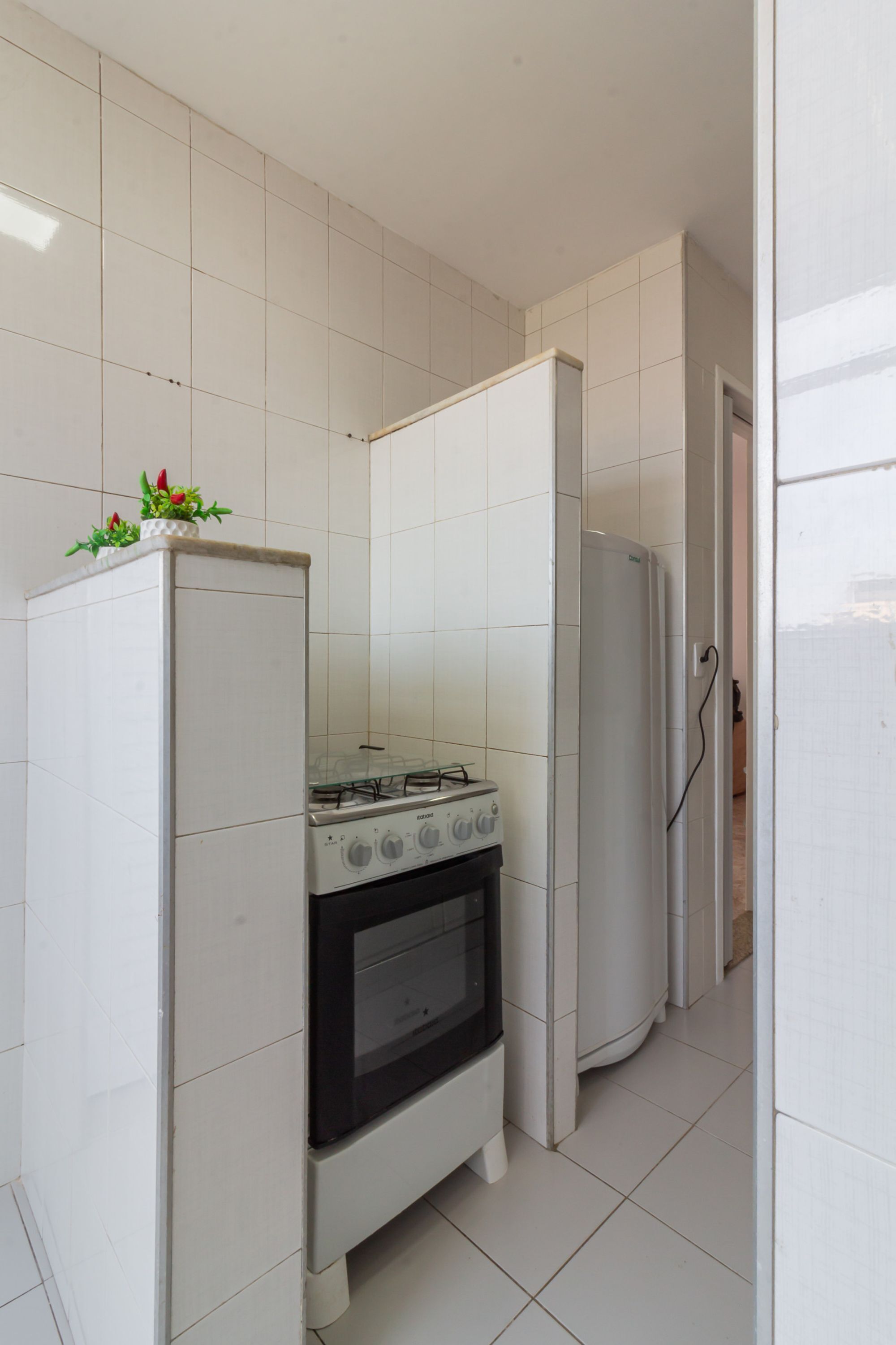 Una cocina con gabinetes blancos, una estufa a gas y un refrigerador.