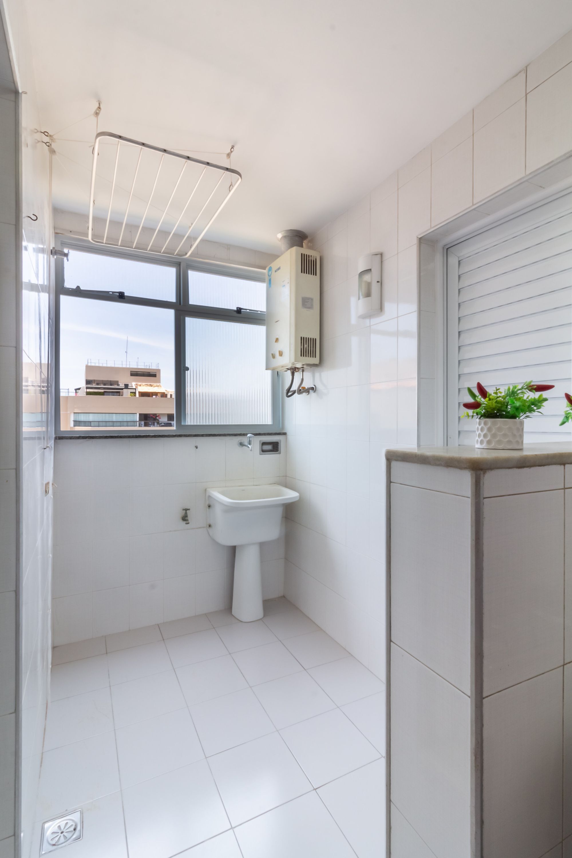 A small, clean bathroom with a window, a sink, a towel rack, and a potted plant.