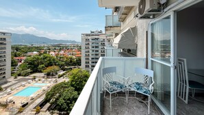 Un balcón con vista a una piscina, una silla y un aire acondicionado Samsung.