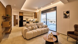 A modern living room with a sofa, a coffee table, and a chair. - POLYTELIA | Luxury Living (Hersonissos)