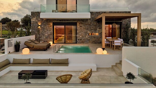 A modern two-story house with a stone facade, a glass balcony, a swimming pool, and outdoor seating. - POLYTELIA | Luxury Living (Hersonissos)