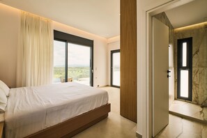 Una camera da letto con un letto grande, una porta scorrevole in vetro per un balcone e vista sull'esterno.