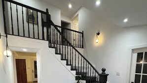 Una escalera con barandillas negras y un piso a cuadros blanco y negro.