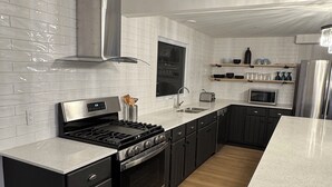 Una cocina moderna con baldosas blancas tipo metro, electrodomésticos de acero inoxidable y muebles oscuros.