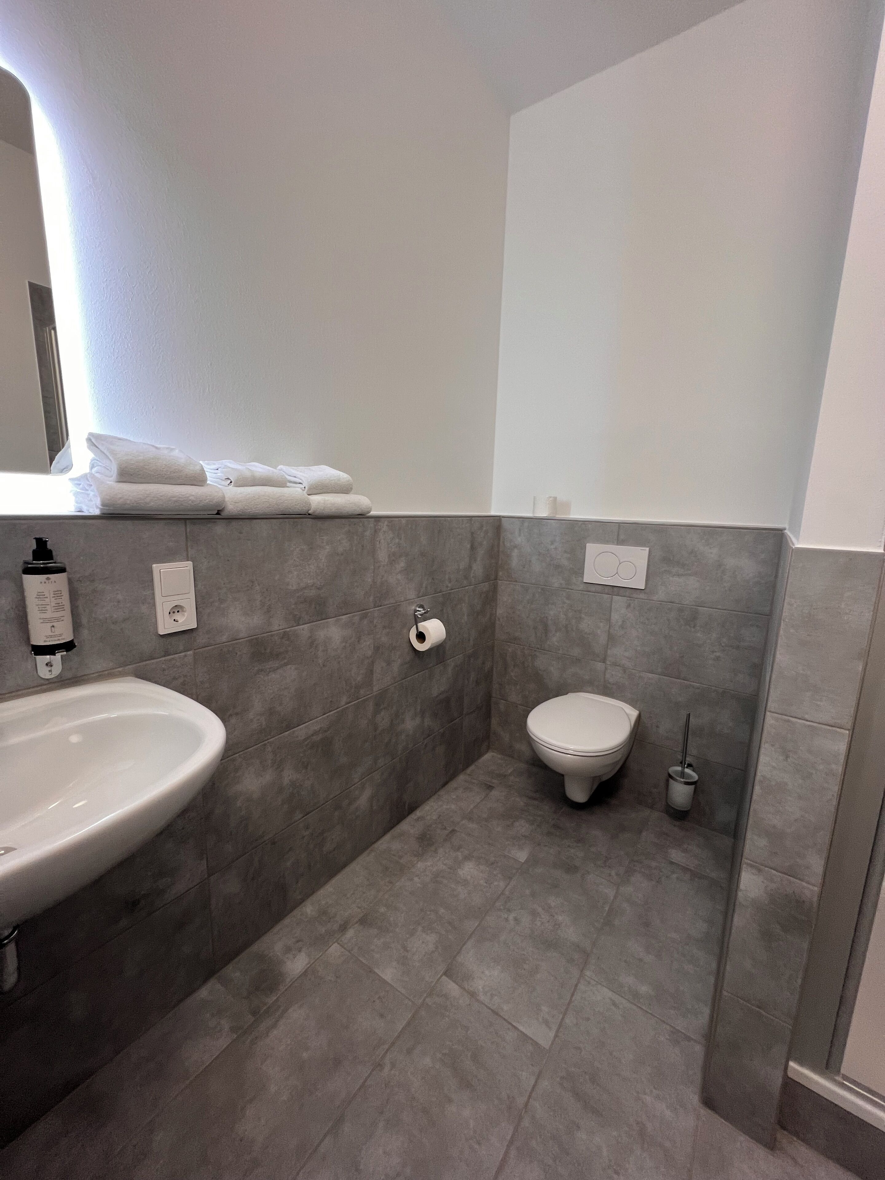 Casa de banho com lavatório branco, sanita e porta-toalhas.