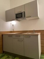 Cozinha compacta com micro-ondas, pia e armários.