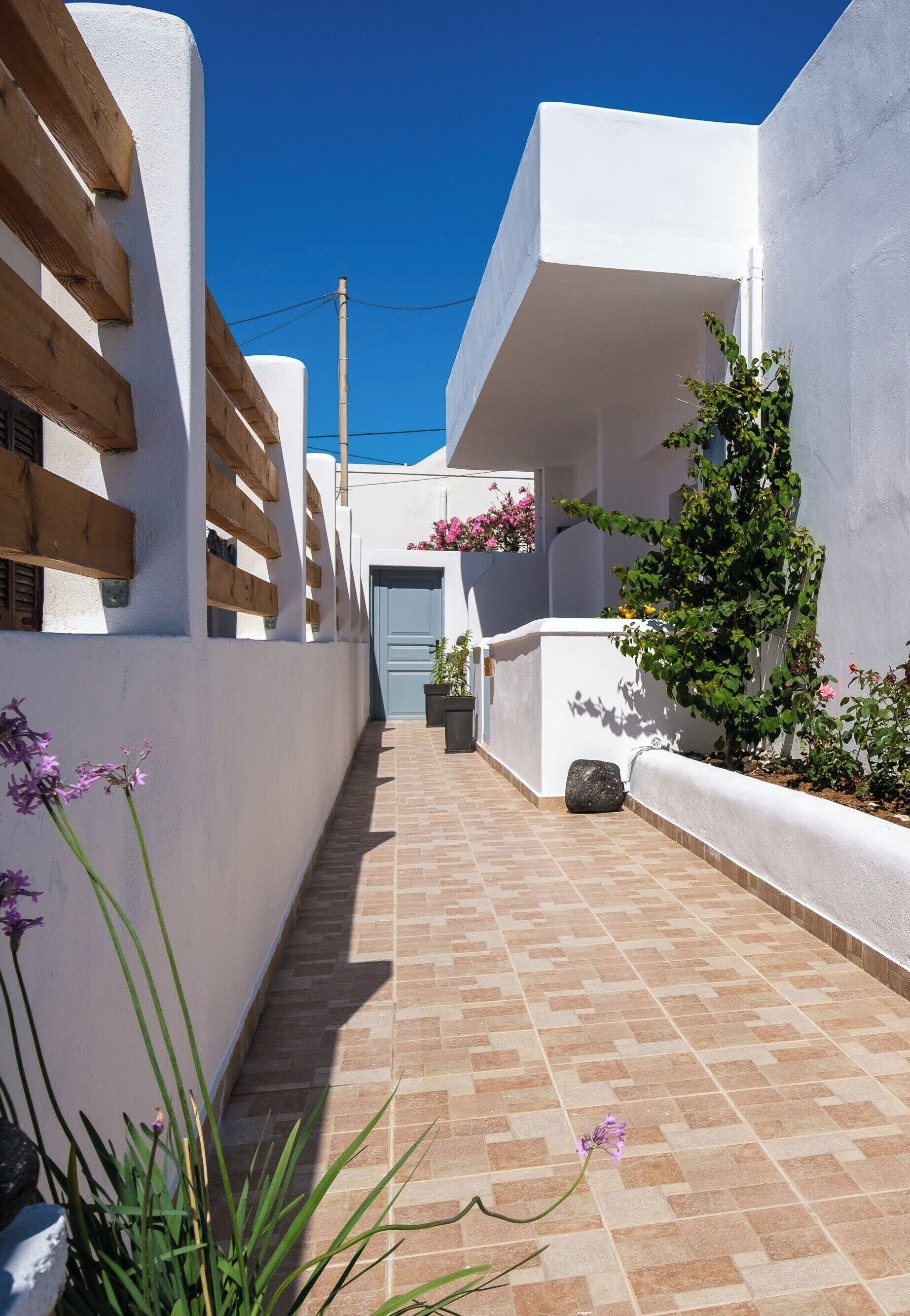 A narrow alleyway with white walls, wooden beams, and a tiled floor.