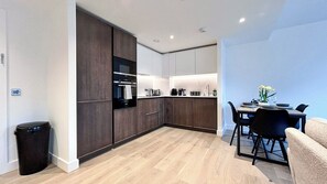 Eine moderne Küche mit dunklen Holzschränken, einem eingebauten Backofen und einem Essbereich mit Tisch und Stühlen.