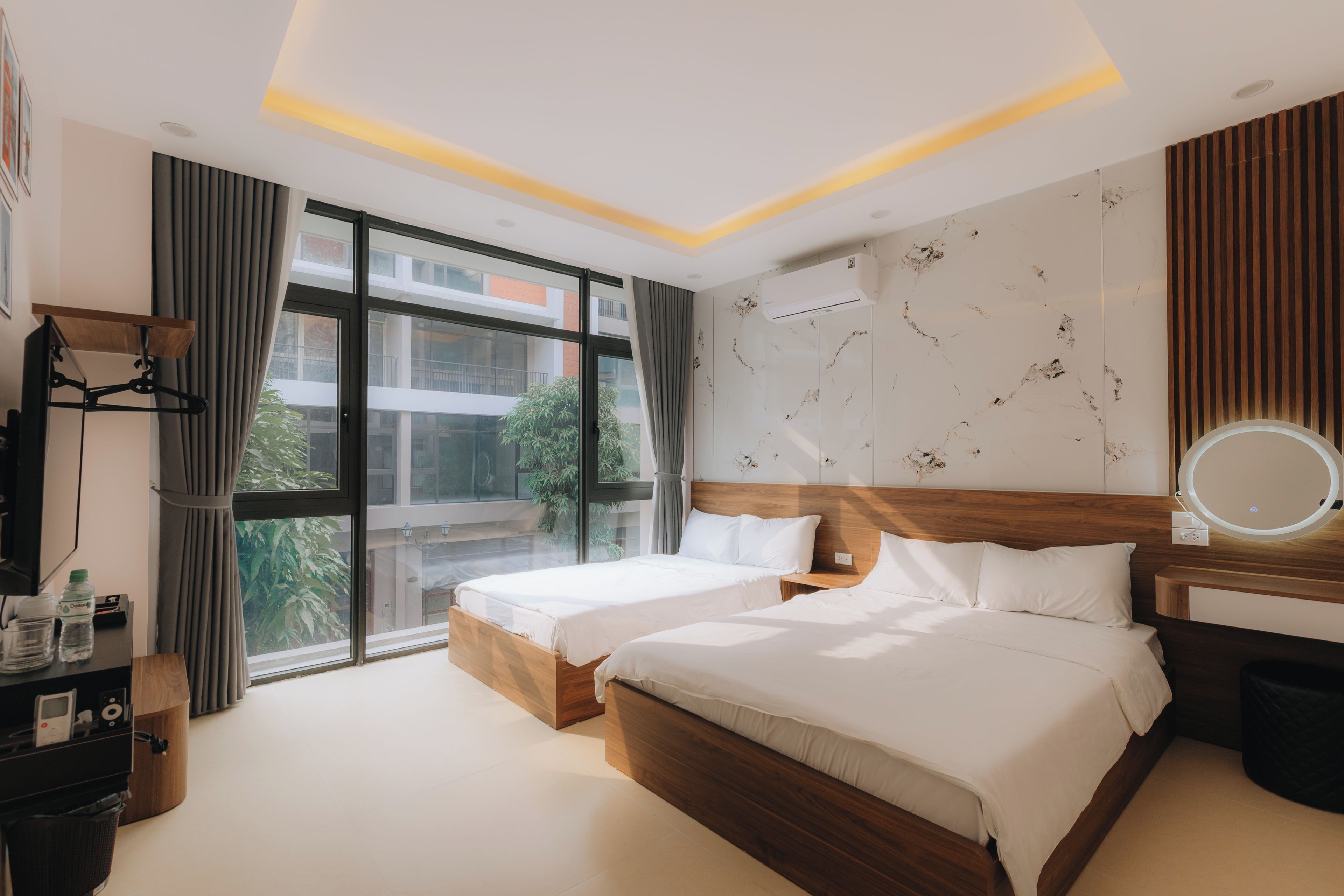 Une chambre d’hôtel avec deux lits, une grande fenêtre, un téléviseur à écran plat et une table de chevet.
