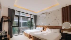 A hotel room with two beds, a large window, a flat-screen TV, and a bedside table.