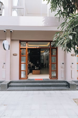 Entrada de hotel con diseño moderno, que incluye un puerta de cristal y una escalera que conduce al interior.