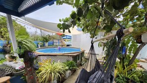 Ein Garten mit Schwimmbecken, einer Hängematte und verschiedenen Topfpflanzen.