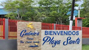 Ein Schild mit der Aufschrift 'Guánica Playa Santa' und einem Krabbenlogo, das einen Strandort kennzeichnet.