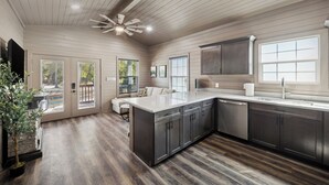 A modern kitchen with dark wood cabinets, a large island, and a ceiling fan. - Everstead Cottage - Cabin 3 (Plantersville)