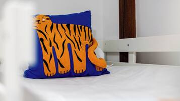 A bed with a white mattress and a blue pillow featuring a tiger design.