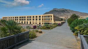 Un sendero que lleva a un edificio, con una montaña al fondo.