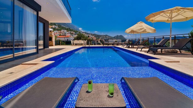 A rooftop pool with clear blue water, lounge chairs, and umbrellas. - Villa Vala in Kalkan (Kaş)