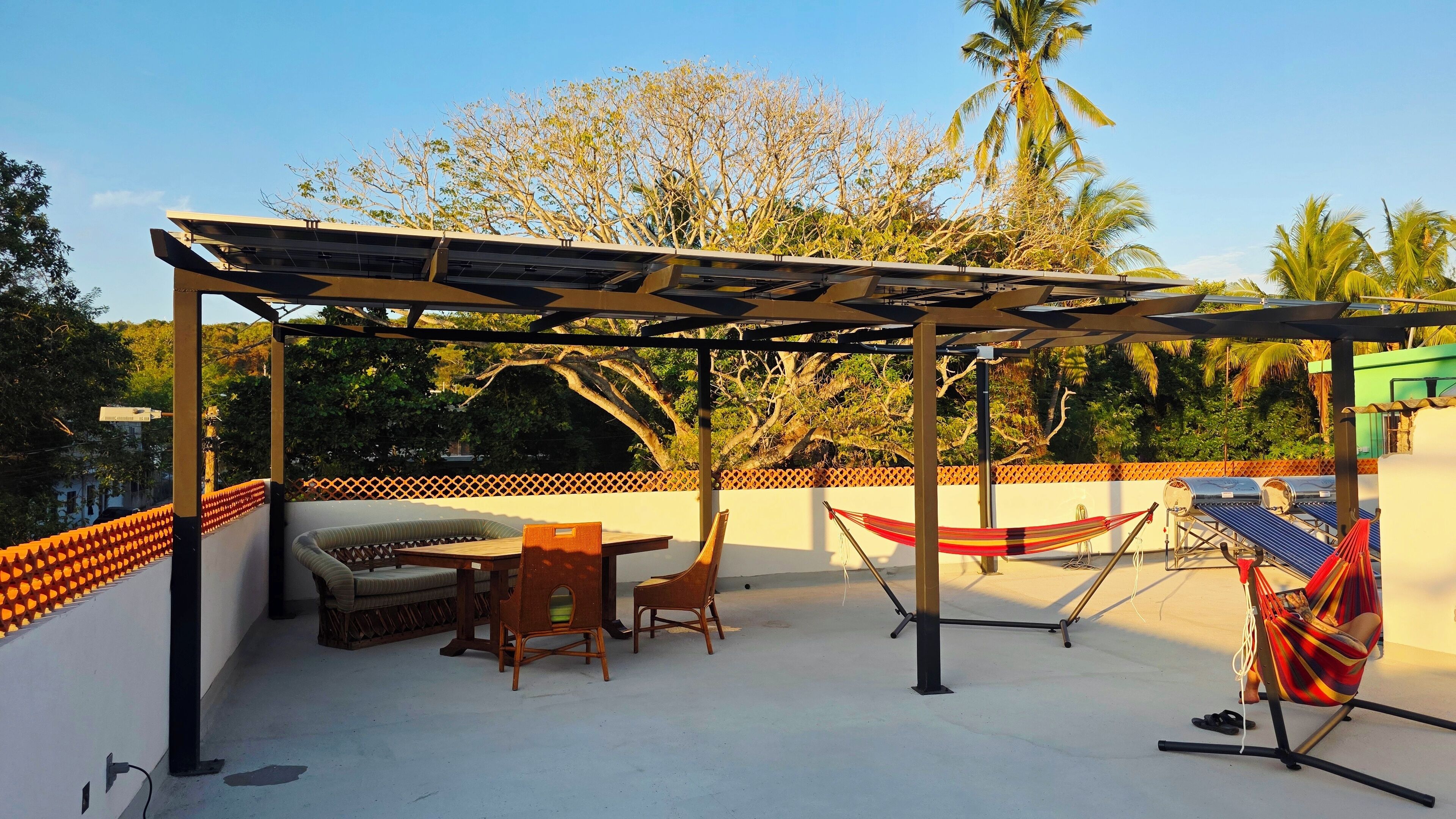 A rooftop patio with a pergola, seating area, and hammocks.