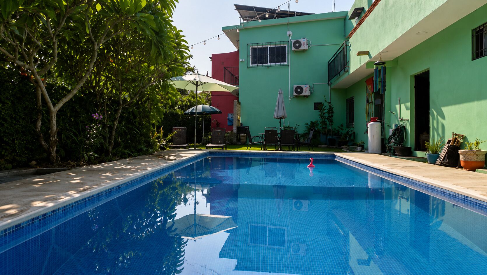 Ein rechteckiger Pool mit glasklarer, blauer Wasserfläche, umgeben von einer gefliesten Sonnenterrasse.