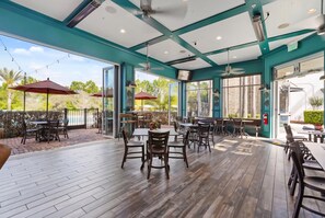 Eine Außenpatio-Terrasse mit Holzboden, Tischen, Stühlen und Sonnenschirmen.