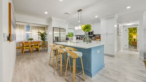 Une cuisine moderne dotée d’un îlot central, de tabourets de bar et d’un coin repas avec une table et des chaises.