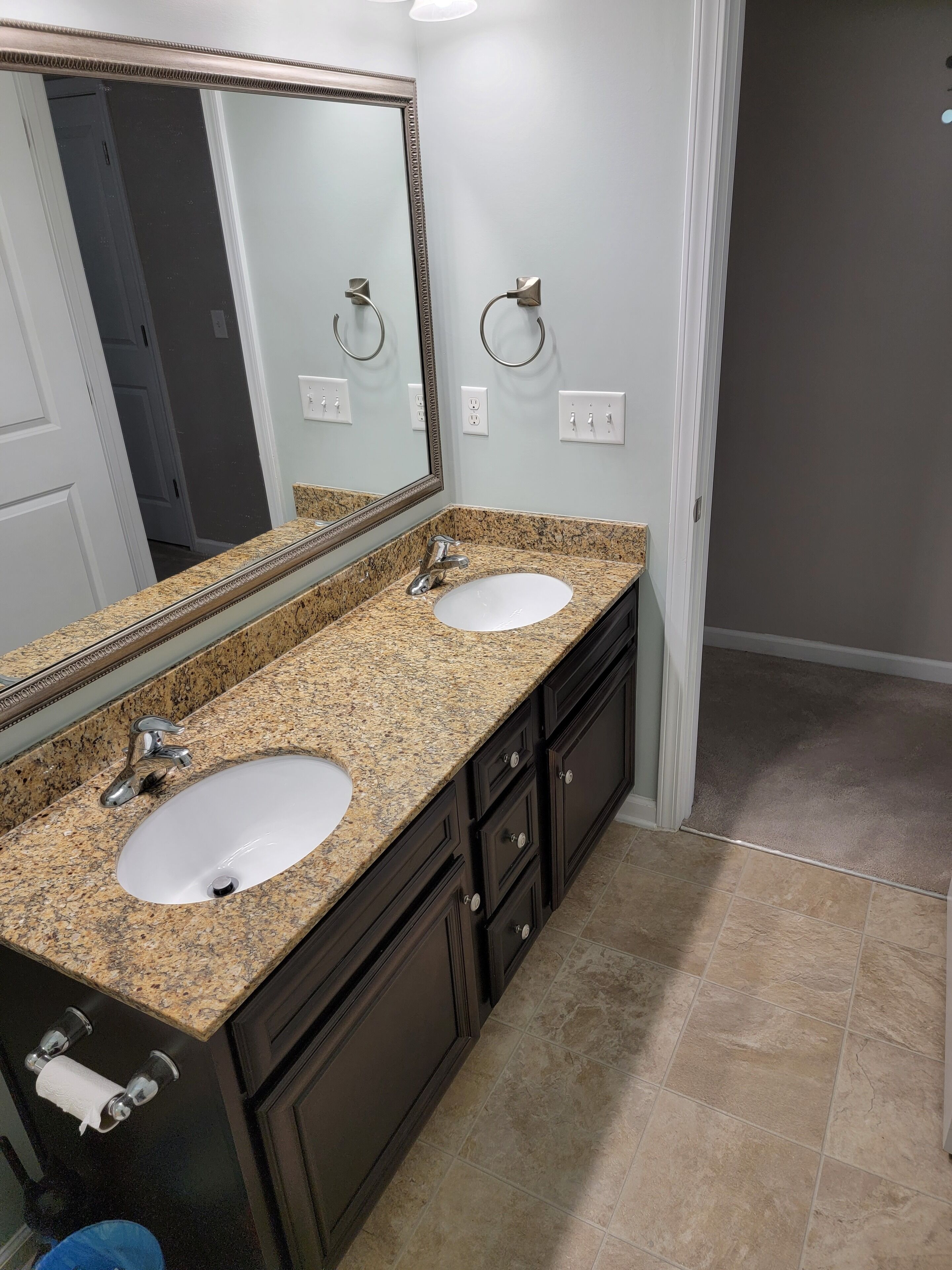 Un baño con dos lavamanos, un espejo grande y muebles oscuros.