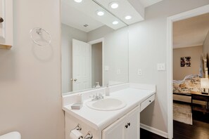 Un baño moderno con lavamanos, espejo y tocador blancos.