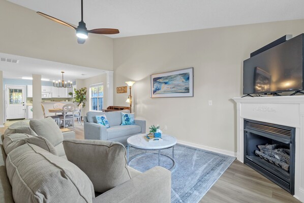 A living room with a fireplace, a television, and a dining area with a chandelier. - Chapin 2/2 Remodeled in 2025 (Chapin)