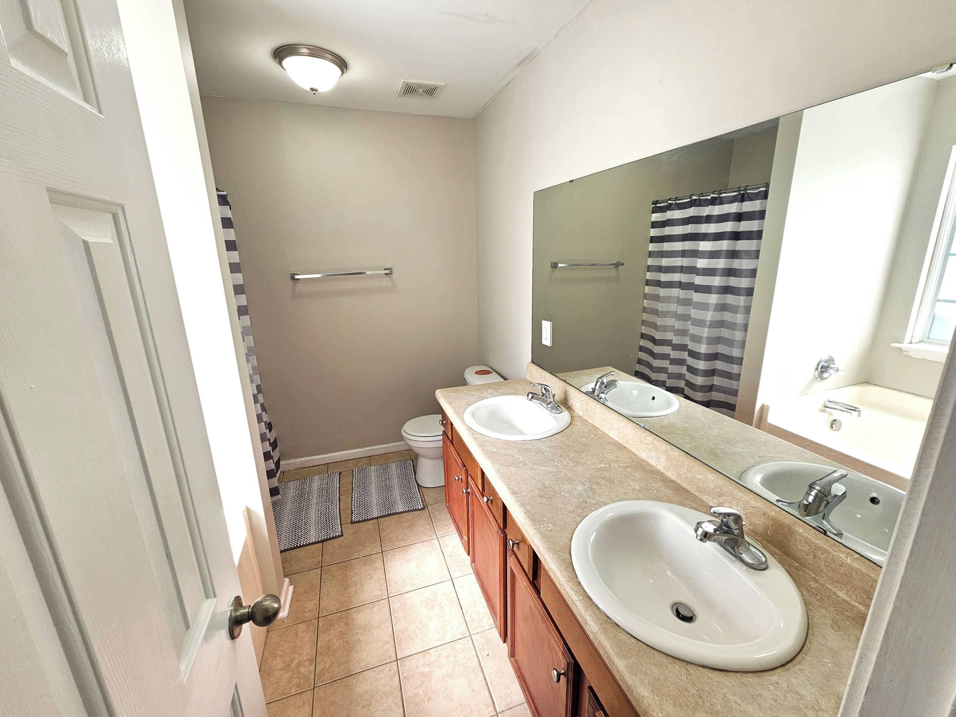 A bathroom with two sinks, a large mirror, and a shower.