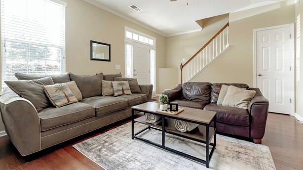 A living room with a brown sofa, a coffee table, and a ceiling fan. - Classy 3 br Townhouse (Lexington County)