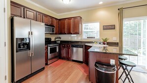 A kitchen with wooden cabinets, stainless steel appliances, a window, and a sign reading "Toscana Bistro." - Classy 3 br Townhouse (Lexington County)