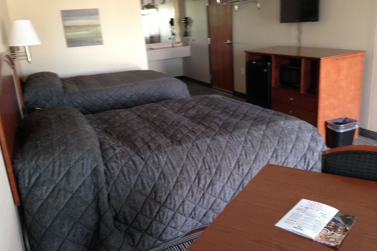 A hotel room with a bed, a desk, a chair, a television, a mirror, and a window.