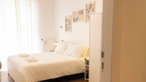 Une chambre bien rangée, avec un lit, des tables de chevet, une armoire et des œuvres d’art accrochées au mur.